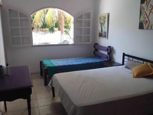 ein Schlafzimmer mit zwei Betten und einem Fenster in der Unterkunft Casa de Praia Itacimirim Bahia in Camassari
