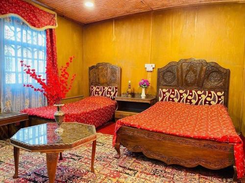 a bedroom with two beds and a table in a room at Houseboat Bendmeer Heritage in Srinagar