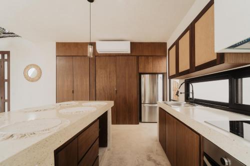 a kitchen with wooden cabinets and a counter top at Villa Viento 4br 8pp Private Pool Rooftop Security in Tulum