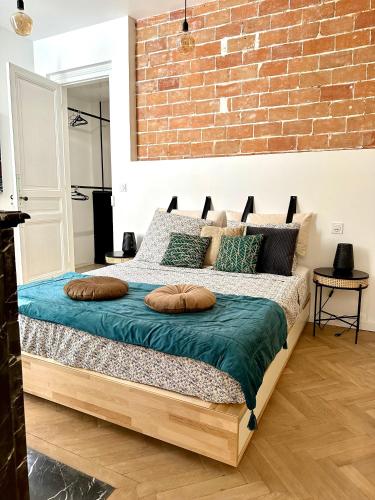 une chambre avec un grand lit avec un mur de briques dans l'établissement Charmante Maison La Libournaise +parking, à Libourne