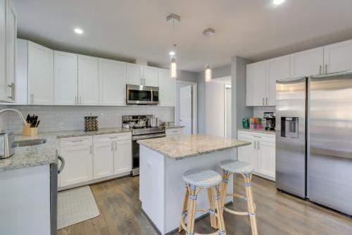 a kitchen with white cabinets and bar stools at 8 Mi to National Mall Quiet Cheverly Apt in Landover