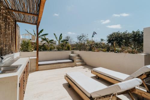 a patio with two lounge chairs and a table at Villa Viento 4br 8pp Private Pool Rooftop Security in Tulum