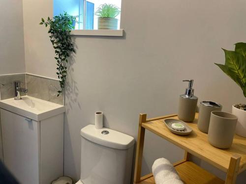 a bathroom with a toilet and a sink and a table at Dumfries House By MGroupSA in Treherbert