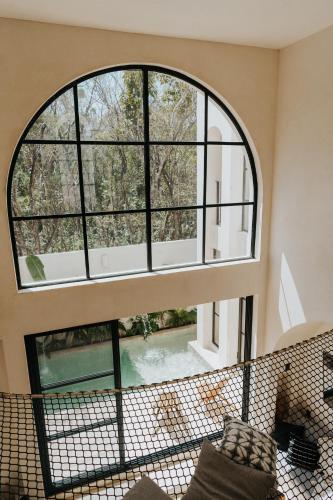 an arched window in a living room with a view of a pool at Villa Viento 4br 8pp Private Pool Rooftop Security in Tulum