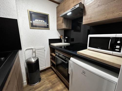 Il comprend une petite cuisine équipée d'un four micro-ondes et d'un comptoir. dans l'établissement Appartement au pied des pistes pour 4 pers, balcon sud, centre des Menuires, proche commerces - FR-1-452-184, aux Menuires