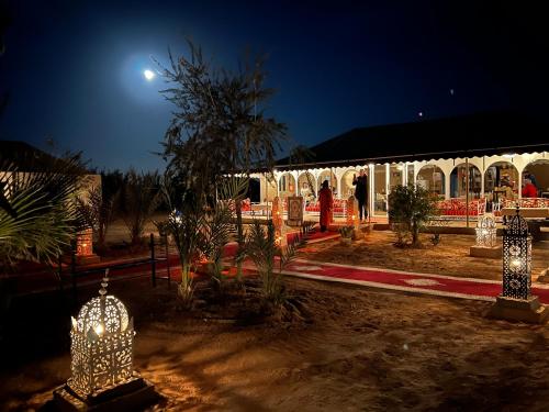 Sahara Majestic Luxury Camp في مرزوقة: مبنى في الليل مع انارة في ساحة