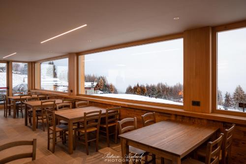 a restaurant with wooden tables and large windows at Chalet Baita del Sole in Teglio