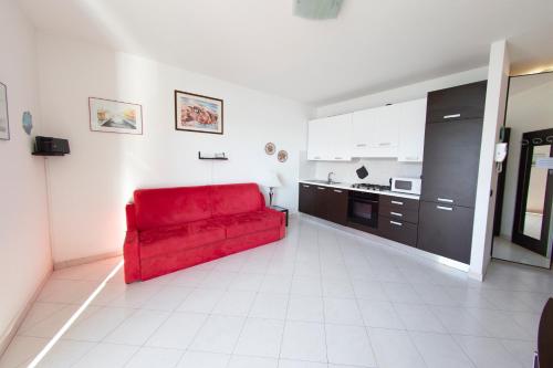 un sofá rojo en una habitación con cocina en Deluxe finestra sul lago, en Bellano