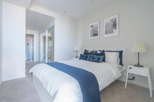 a white bedroom with a large bed with blue accents at Stunning 1BD Haven with Panoramic City Views in Brisbane