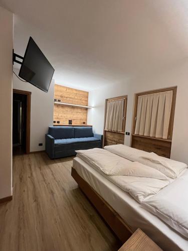 a bedroom with two beds and a blue couch at Chalet Baita del Sole in Teglio