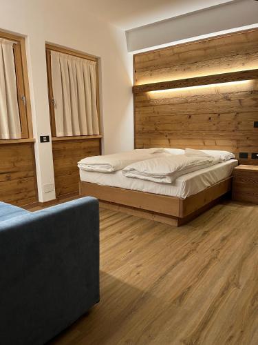 a bedroom with a large bed and wooden floors at Chalet Baita del Sole in Teglio