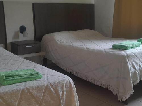 two beds in a room with green towels on them at Hosteria Catalina in Villa Carlos Paz