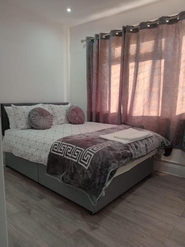 Good priced double bed rooms in harrow with shared bathrooms في Hatch End: غرفة نوم بسرير ونافذة مع ستائر