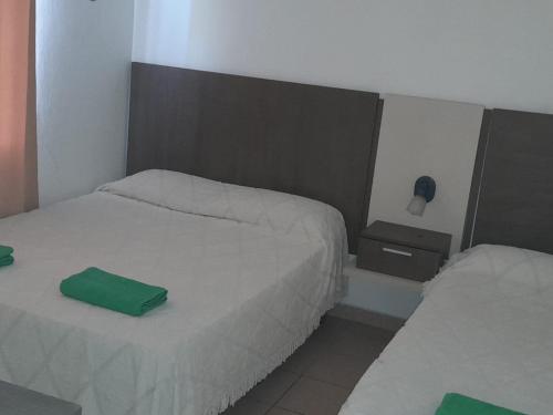 a bedroom with two beds and a green pillow on the bed at Hosteria Catalina in Villa Carlos Paz
