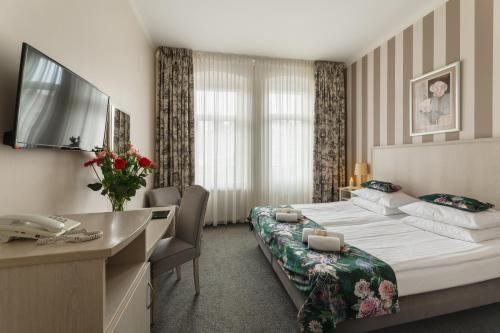 Habitación de hotel con 2 camas y escritorio en Hotel Amalia en Kudowa-Zdrój