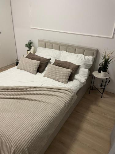 uma cama grande com lençóis brancos e almofadas em AirPort Apartment em Varsóvia