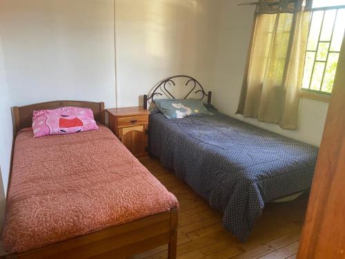 1 dormitorio con 2 camas, mesa y ventana en Cabaña quilpue, en Quilpué