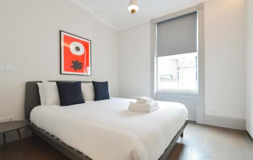 a bedroom with a large white bed with a window at Soho Deluxe 1 Bedroom Apartment by Concept Apartments in London