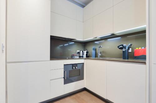 a kitchen with white cabinets and a stove at Soho Deluxe 1 Bedroom Apartment by Concept Apartments in London