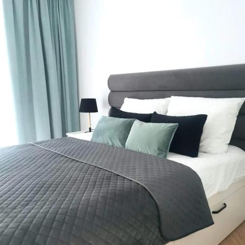 a large bed with a gray comforter and pillows at Plażowa Park Apartamenty in Międzywodzie