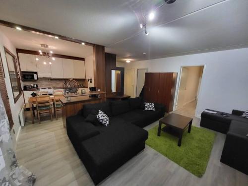 sala de estar con sofá negro y cocina en Two bedroom apartment right next to Santapark, en Rovaniemi