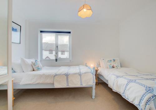 two beds in a room with a window at Millies in Padstow