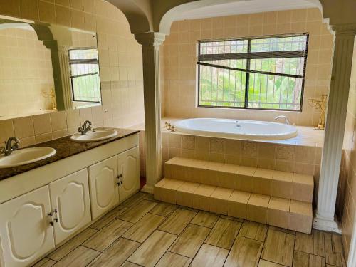 łazienka z wanną, 2 umywalkami i oknem w obiekcie Spacious peaceful 5 bedroom house w mieście Pretoria