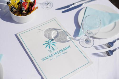 a table with a menu and a wine glass at Elea Beach Hotel in Dassia