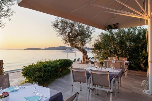 a restaurant with tables and a view of the water at Elea Beach Hotel in Dassia