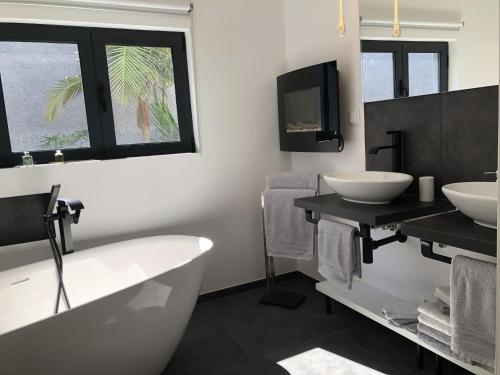 ein Badezimmer mit zwei Waschbecken und einer Badewanne sowie einem TV in der Unterkunft Casa da Arvore in Arco da Calheta