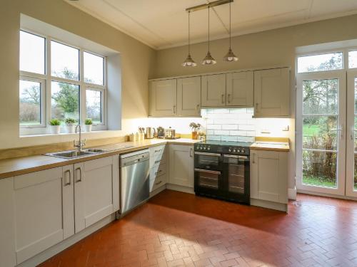 a kitchen with white cabinets and appliances and windows at Tirallen in Llanwrda