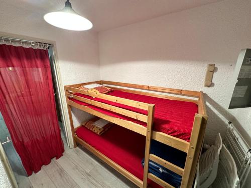 a bedroom with two bunk beds with red sheets at Studio Cabine avec Jardinet à Corrençon, Navette Gratuite, Proche Village et Pistes de Ski - FR-1-515-52 in Corrençon-en-Vercors