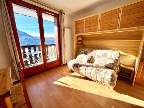 un salon avec un canapé et une grande fenêtre dans l'établissement Charmant studio au pied des pistes, animaux admis - FR-1-505-79, à Notre-Dame-de-Bellecombe