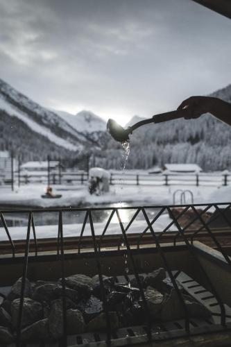 a bird drinking water out of a bird feeder at Alpinhotel Berghaus spa in Tux