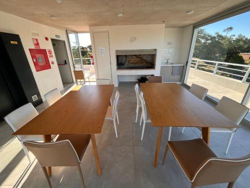 Habitación con 2 mesas, sillas y chimenea. en Edificio Pinheiros en Punta del Este