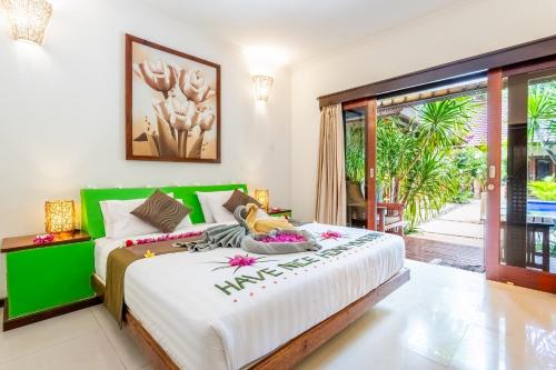 a bedroom with a large bed with a green headboard at Senang Villa Gili Air in Gili Air