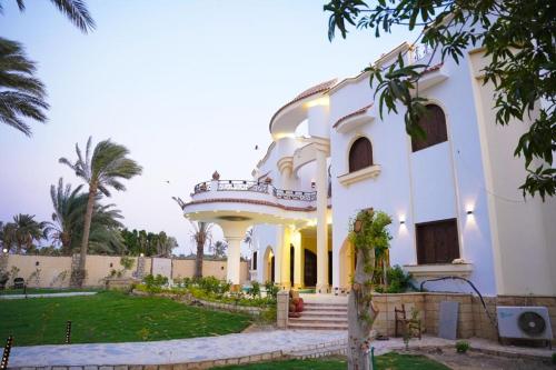 a large white building with a balcony and a yard at Tunis Beach Families Only in Fayoum Center