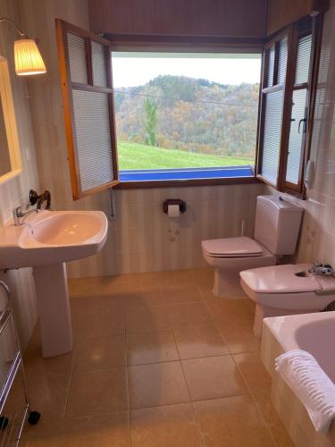 Un baño con lavabo, inodoro y ventana. en VILLA ACEBO, en Arboleya