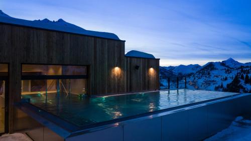 a house with a swimming pool in front of mountains at Das Kohlmayr Superior in Obertauern