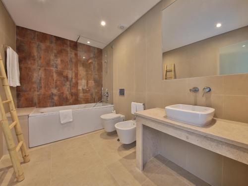 een badkamer met 2 toiletten, een bad en een wastafel bij Winter @Prainha in Alvor