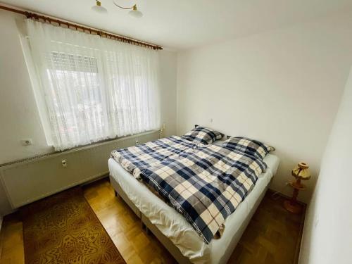 a bedroom with a bed with a checkered blanket and a window at Ferienwohnung Struth-Helmershof in Struth-Helmershof