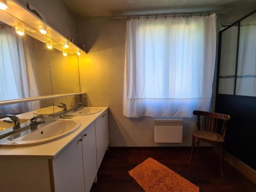 un bagno con due lavandini, uno specchio e una sedia di Maison avec piscine chauffée, bain nordique et grand jardin près d'Argenton-sur-Creuse - FR-1-591-63 a Le Menoux