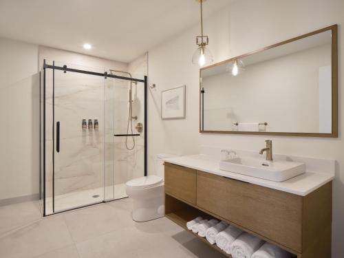 a bathroom with a shower and a sink and a toilet at Hôtel Expérience - Quartier Des Marinas in Magog-Orford