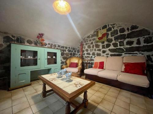 un salon avec un canapé et une table dans l'établissement Gîte confortable en hameau calme près du Puy en Velay – 2 chambres, équipement bébé, terrain fermé - FR-1-582-141, à Lantriac