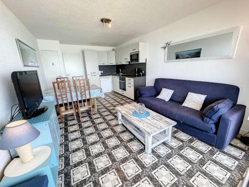 un salon avec un canapé bleu et une table dans l'établissement Appartement en front de mer avec balcon et parking privatif - FR-1-361-360, à Jullouville