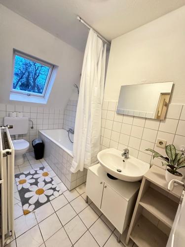 a bathroom with a sink and a tub and a toilet at Modern Apartment in Gütersloh Avenwedde in Gütersloh