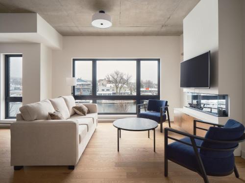 a living room with a couch and a table and chairs at Hôtel Expérience - Quartier Des Marinas in Magog-Orford