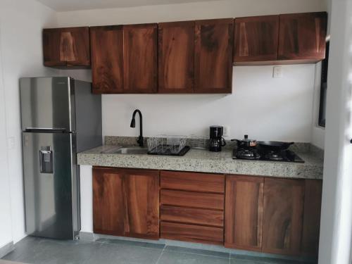 cocina con armarios de madera y nevera de acero inoxidable en dept Miraflores en Zihuatanejo