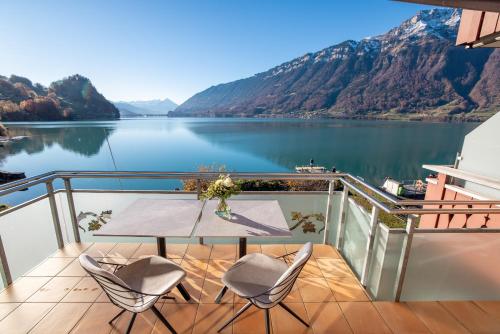 a table on a balcony with a view of a lake at Chalet Apartments Iseltwald in Iseltwald