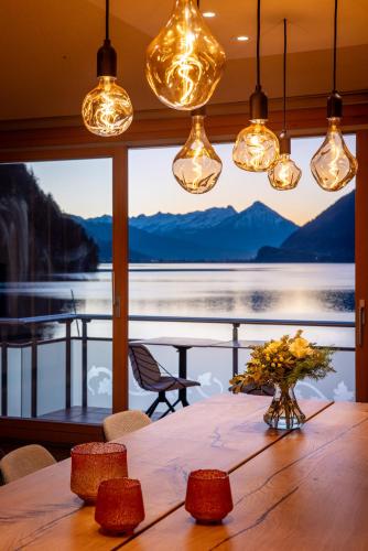 a dining room table with a view of a lake at Chalet Apartments Iseltwald in Iseltwald